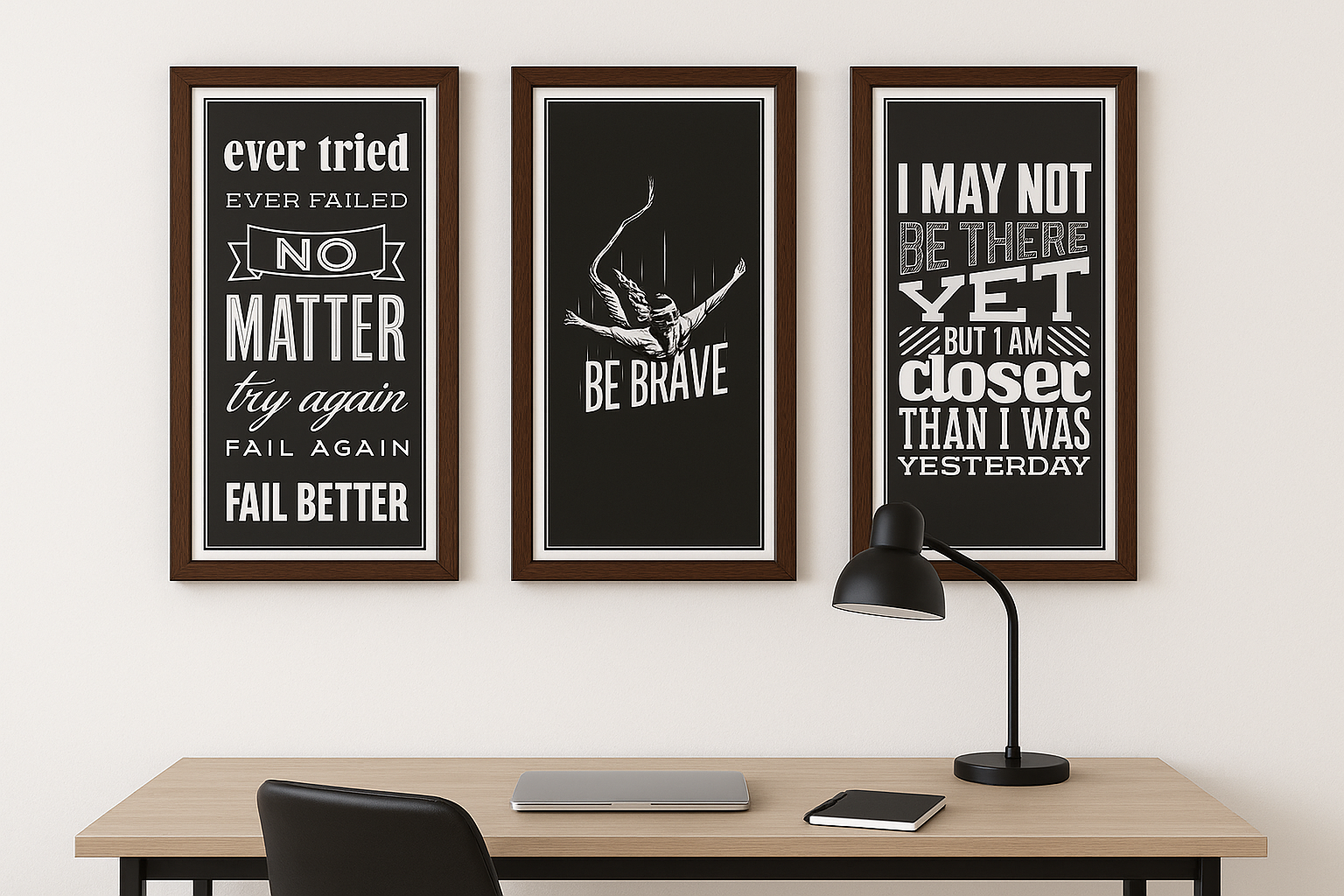 Three motivational framed prints on a wall above a desk with a lamp.